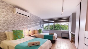 A modern hotel room with two beds, a radiator, a window with a view, and a wall-mounted air conditioner. - U-GO Faro Tequendema (Cartagena)
