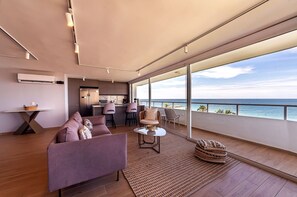 Un interior moderno con un sofá, comedor y vista al mar.