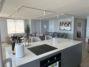Une cuisine moderne dotée d’un îlot central, d’appareils électroménagers intégrés et d’un coin repas avec une grande table.