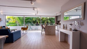 A modern living room with a large window, a sofa, a dining area, and a kitchen counter. - U-GO Faro Tequendema (Cartagena)