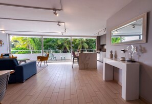 Una sala de estar moderna con un ventanal grande, un sofá, una zona de comedor y una encimera de cocina.