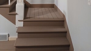 Un escalier muni d’une rampe, un tableau accroché au mur et une photographie encadrée au-dessus.