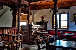 A rustic interior with wooden furniture, a fireplace, and a red cushioned bench. - Hotel Mitikas (Elassona)