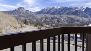 Une vue sur les montagnes depuis un balcon doté d’une balustrade, un parking et une route qui serpente à travers le paysage.