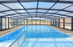 A covered swimming pool with a glass ceiling, surrounded by metal railings. - Nice home in Olonzac with heated swimming pool (Olonzac)