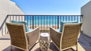 A balcony with wicker chairs and a small table, overlooking a beach and the ocean. - Luxury Oceanfront Couples Retreat- Station 1 Top Floor, Newly Renovated (Wrightsville Beach)