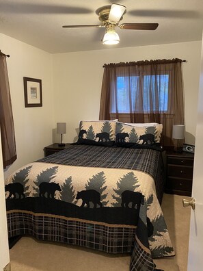 Restful retreat with a large bed, ceiling fan, and window with sheer curtains.