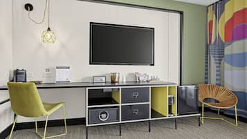 Ein modernes Zimmer mit Flachbildfernseher, Schreibtisch mit Stauraum, Stuhl und einer dekorativen Wandgestalt.