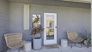 A modern exterior with two wicker chairs, a potted plant, and a door with a number 12.