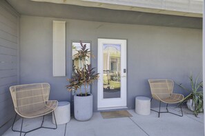 A modern exterior with two wicker chairs, a potted plant, and a door with a number 12. - Mahala Hotel by AvantStay (Palm Springs)