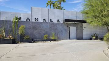 A building with the name 'MAHALA' on the facade, a concrete entrance, and a parking area.