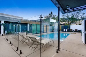 Una piscina al aire libre, sombrillas, sillones reclinables de piscina