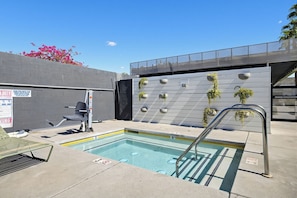 An outdoor swimming pool with a metal ladder, a bench, and a wall with planters. - Mahala Hotel by AvantStay (Palm Springs)