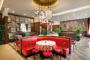 A restaurant with red booths, a bar area, and a wall decorated with framed pictures.