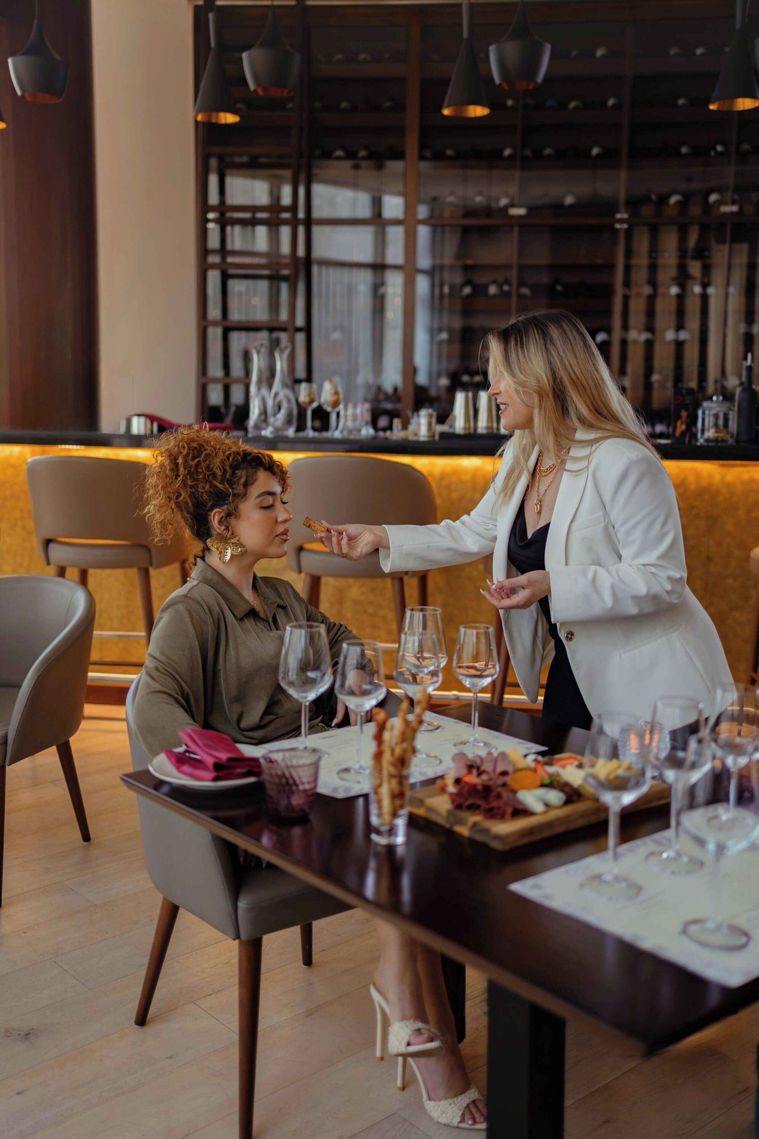A dining area with a bar in the background, a table set with wine glasses and a fruit platter.