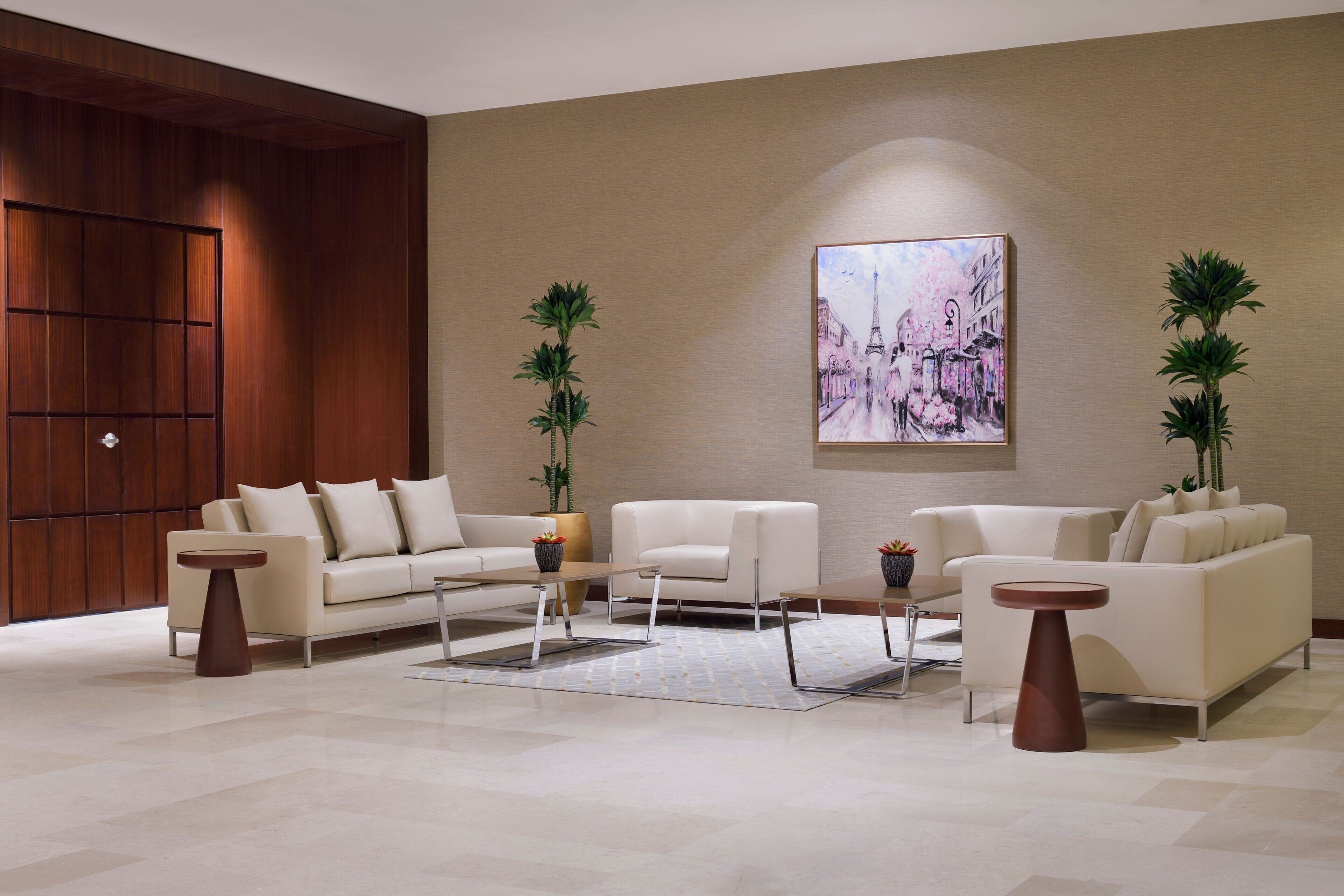 Un salon moderne avec un grand mur recouvert de panneaux en bois, un ensemble de canapés beige, une table basse et deux tables d’appoint.