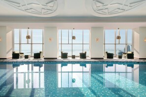 Una piscina interior moderna con paredes de vidrio transparente que ofrecen vistas del paisaje urbano.