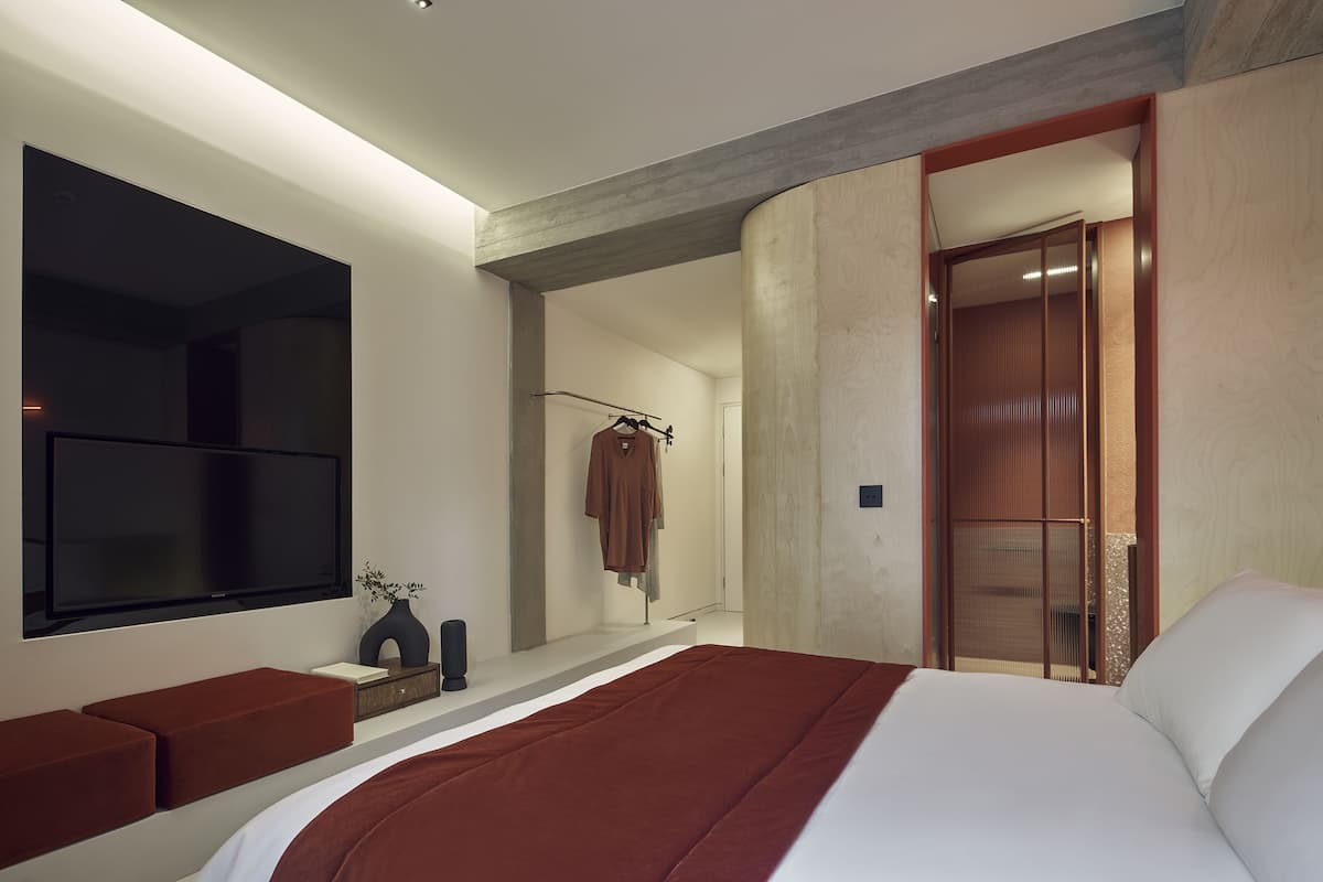 A modern bedroom with a large bed, a flat-screen TV, and a walk-in closet.