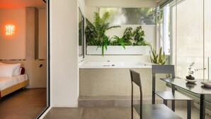 A modern bathroom with a large window, a bathtub, and a sink. There is a bed and a chair in the adjacent room. - The Newel Metaxourgeio by Athens Stay (Athens)