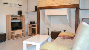 Ein Wohnzimmer mit einer Couch, einem Fernseher, Holzregalen und einer Steinwand.