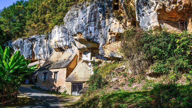 Ein Steinhaus mit rustikalem Aussehen, gelegen in ländlicher Umgebung, mit einer schmalen Straße, die darauf zuführt.