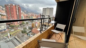 A balcony with a view of a cityscape, including buildings and a mountain.