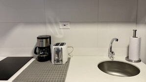 A kitchenette with a coffee maker, toaster, and sink.