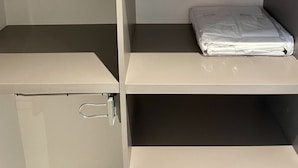 A storage unit with shelves, a small cabinet, and a folded blanket.