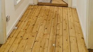 Un estrecho pasillo con piso de madera que conduce a un dormitorio con literas.