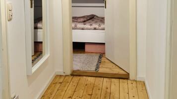 Ein schmaler Flur mit Holzdielen, der zu einem Schlafzimmer mit Etagenbett führt.