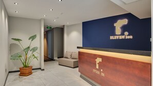 Een ontvangsthal met een blauwe muur, een houten receptiebalie en een potplant.
