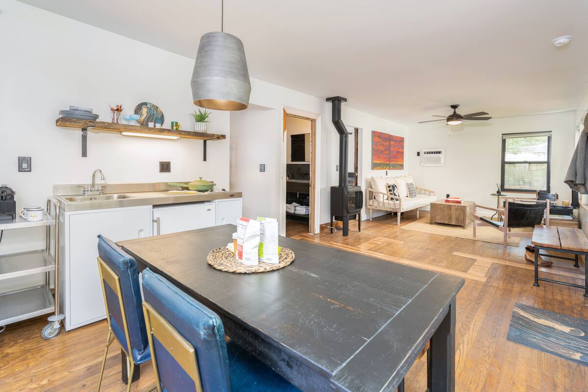 A modern kitchen with a dining area, wooden flooring, and a black stove.