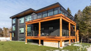 A modern two-story house with large windows, a wooden deck, and a staircase leading to the upper floor. - High-Tech Mountain Luxury, Fitness, Hot Tub & BBQ (The Blue Mountains)