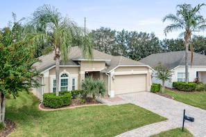 A single-story house with a garage, surrounded by a well-maintained lawn and landscaping.