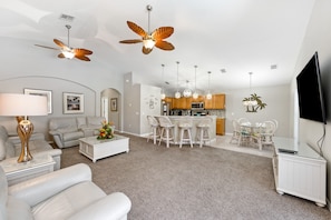 A modern living room with a sofa, coffee table, and a dining area with chairs and a table. - West Haven Joy | 4 bed, 4 bath | Private Pool (Davenport)