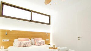 A hotel room with a bed, bedside tables, a window, and a door. - Delight Holiday Home (Playa del Inglés)