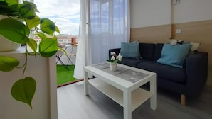 Una sala moderna con un sofá azul oscuro, una mesa de centro blanca y una planta verde.
