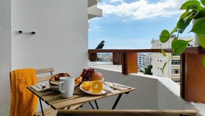 Un balcón con una mesa dispuesta para el desayuno, que incluye croissants, uvas y naranjas.