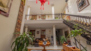 Un vestíbulo amplio con techo alto, una escalera y una mesa central con objetos decorativos.