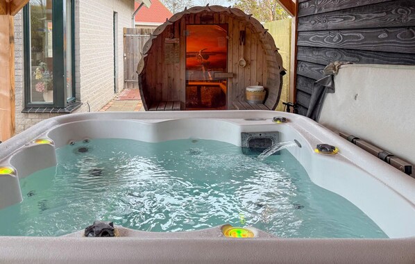 Een hottub met een houten toegangsbogen, een houten buitenkant en een raam met uitzicht op de omgeving.