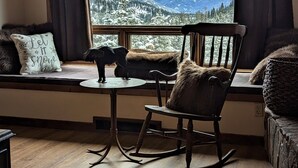 Una camera accogliente con una poltrona a dondolo vicino a una finestra con vista sulle montagne innevate.