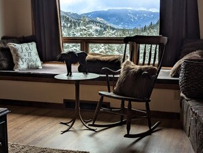 Relax in a serene mountain view room with a comfortable rocking chair and a decorative elephant figurine.