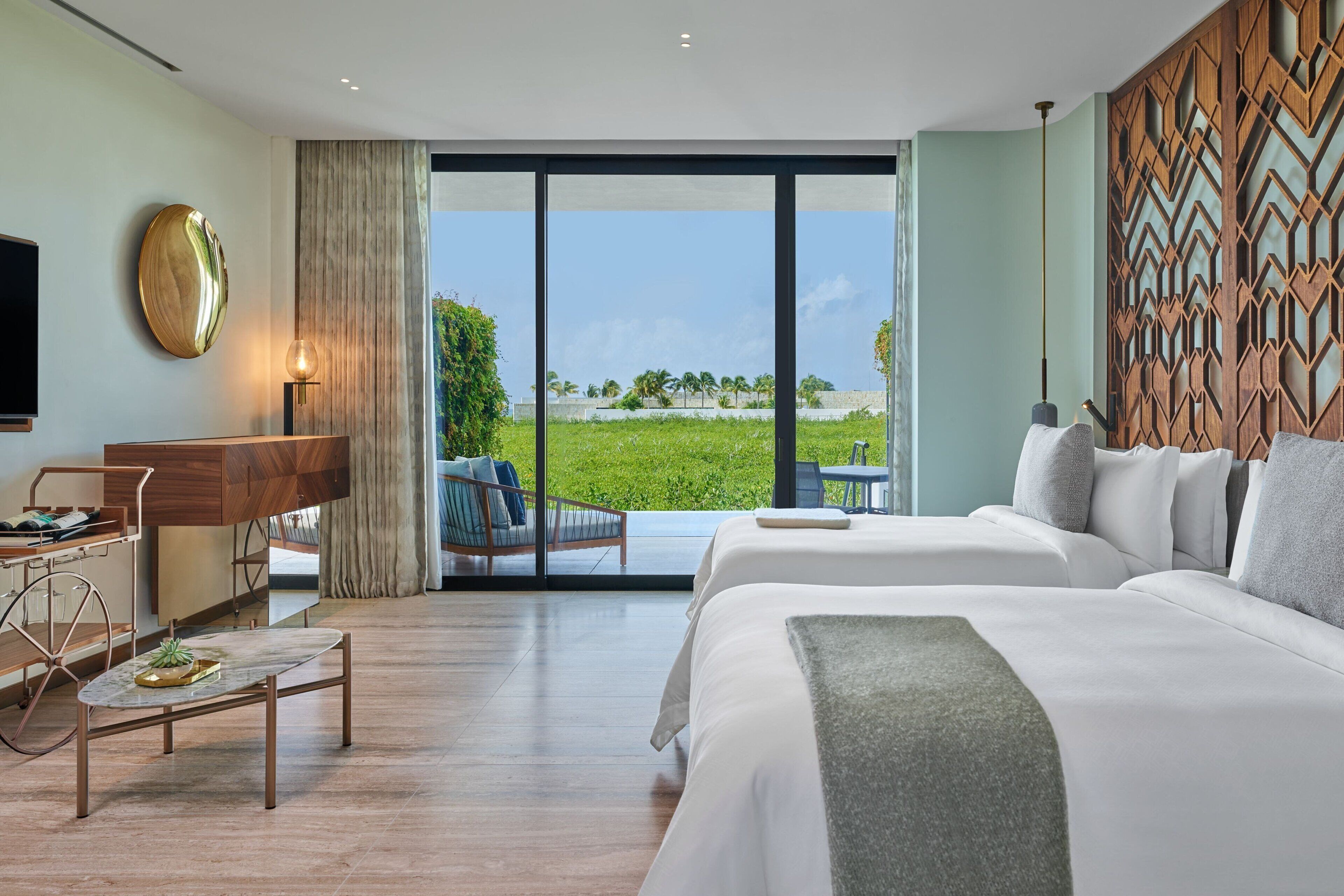 Een hotelkamer met een groot bed, een bureau en uitzicht op een groen landschap.