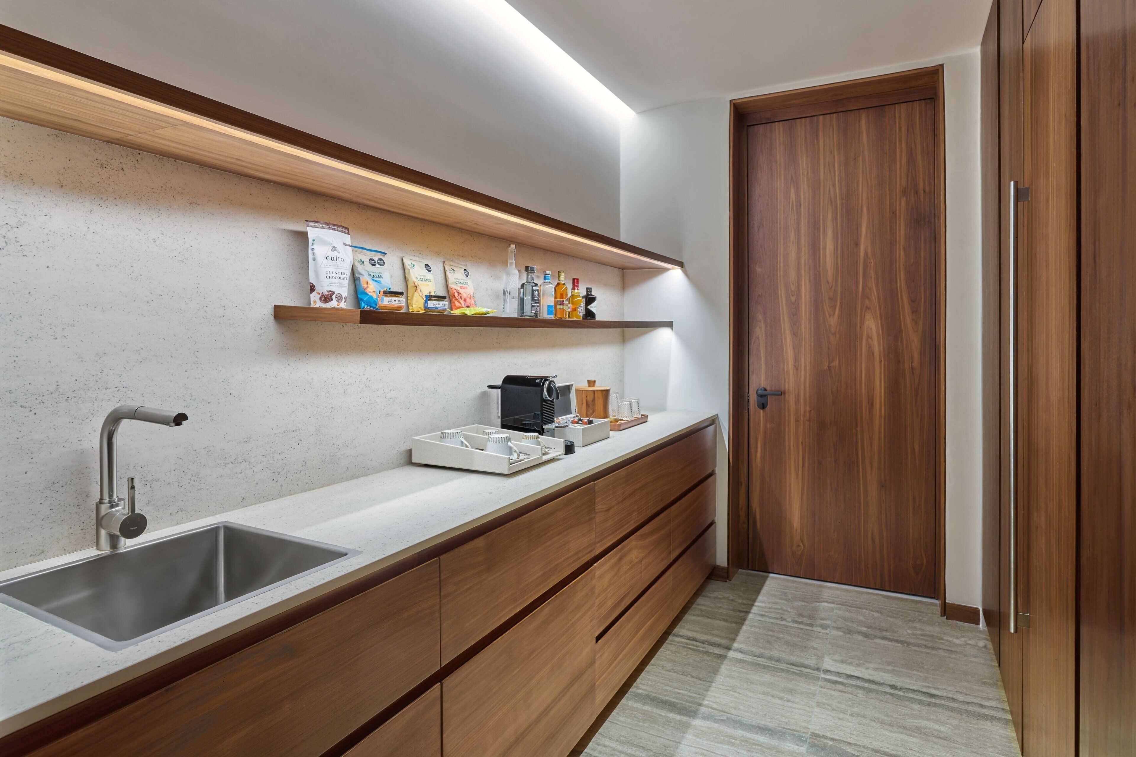 A modern kitchen with a stainless steel sink, wooden cabinets, and a countertop with various items.