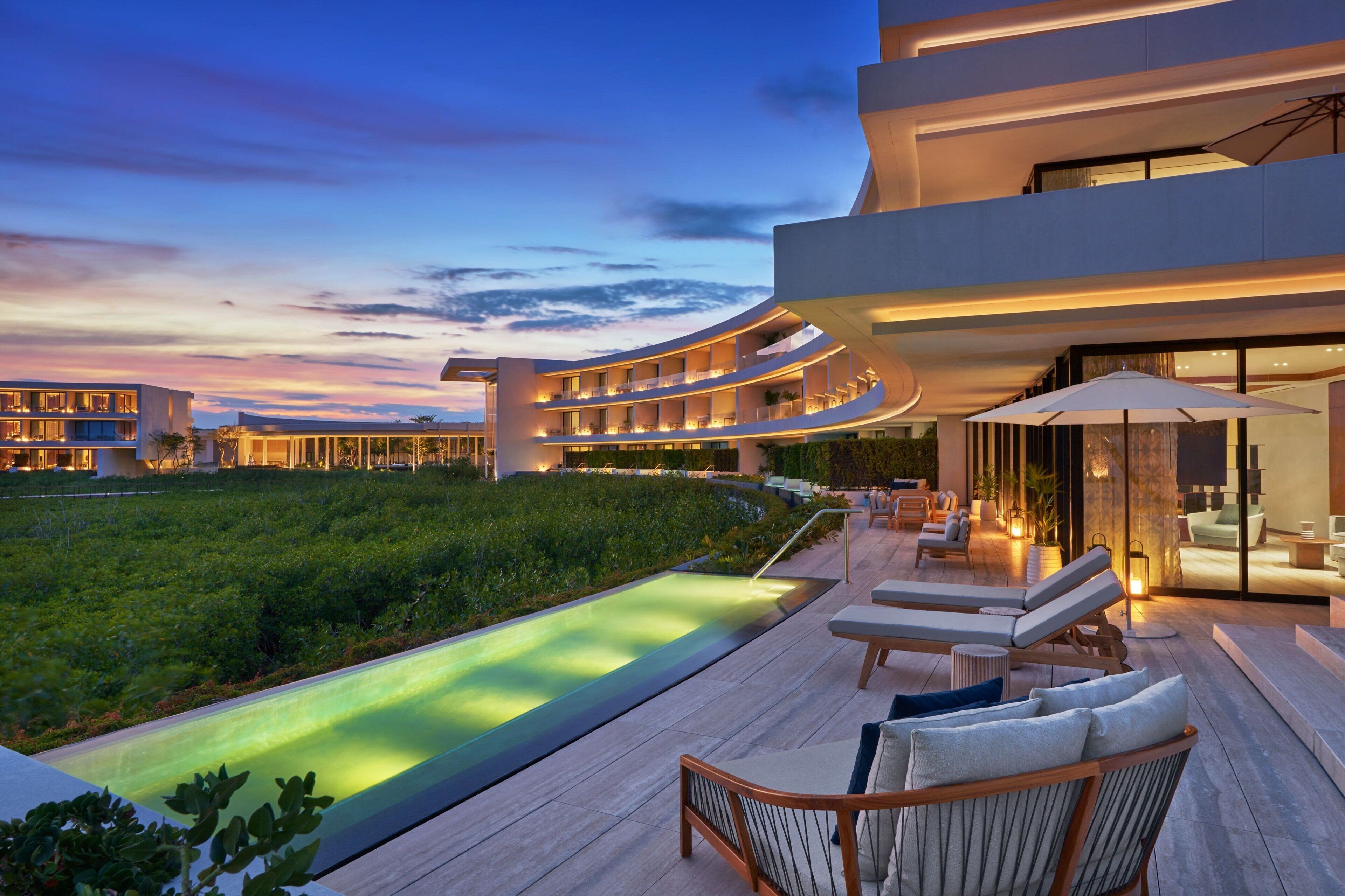 A modern hotel with a pool, outdoor seating, and a landscaped garden.
