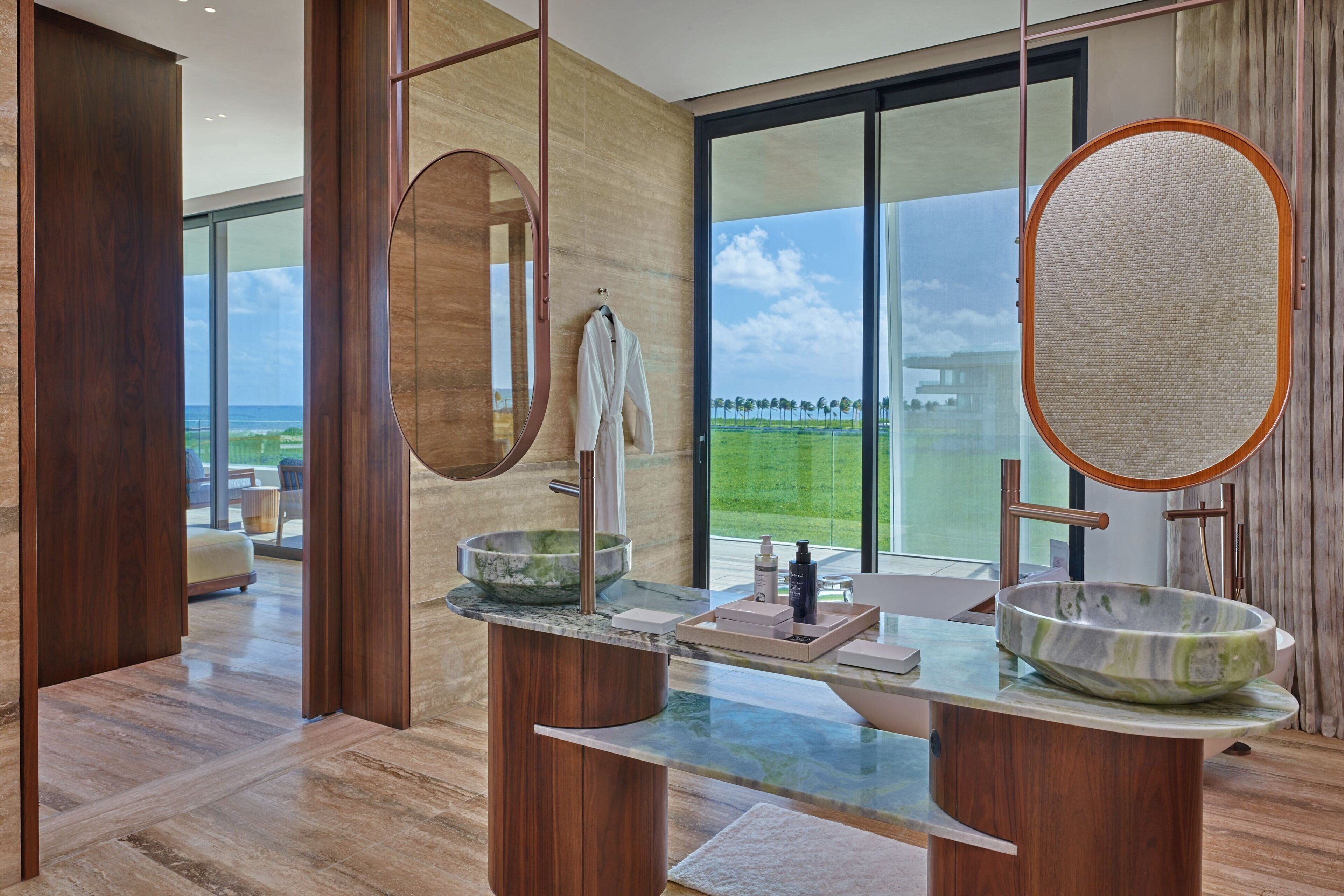 Un baño moderno con un ventanal grande, un tocador de madera y un lavabo.