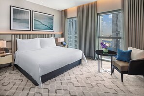 Habitación de hotel con una cama grande, un escritorio, una silla y vistas a la ciudad.