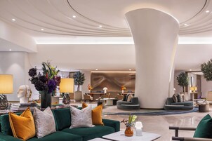 A modern lobby with a green sofa, a large white pillar, and a variety of decorative items.