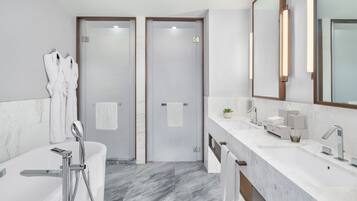 A modern bathroom with a bathtub, a large mirror, and a vanity with a sink.