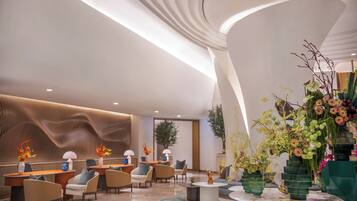 A modern lobby with curved ceiling, seating areas, and decorative plants.